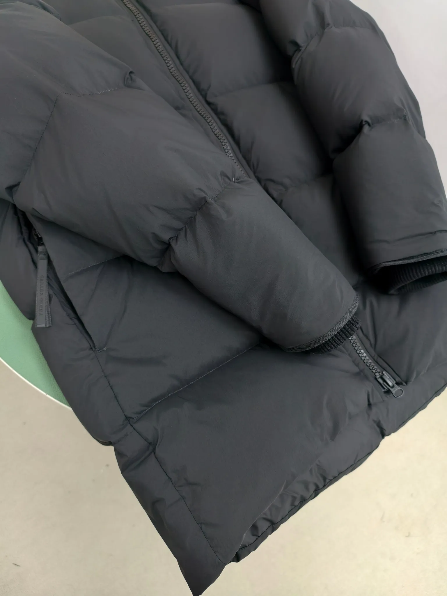 P940 Canada Goose Lawrence Down Jacket The Lawrence Down Jacket provides essential protection for everyday adventures and is made from sustainable Enduraluxe fabric with a durable soft touch. It features a quilted body, an adjustable down hood and a longer hem. Adjustable, down-filled, communicated hood. Two-way center front zipper increases range of motion and ventilation. The chin-protecting suede knit stand-up collar is soft and extra-comfortable. Inset rib-knit cuffs for added comfort and locked in heat. CORDURAD piping at the cuffs hem and reflective double-stripe grip tape at the back. Internal shoulder strap Color: black with red label black with black label azure blue Size: XS-2XL